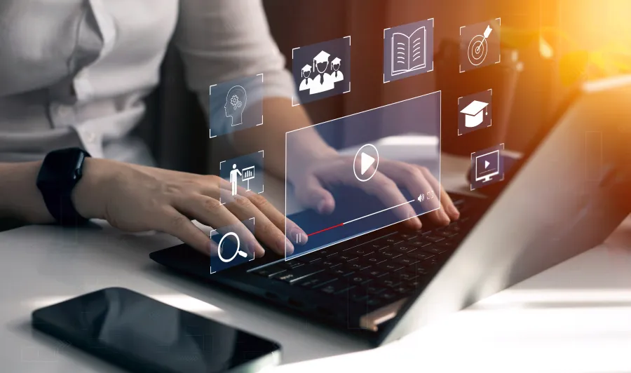 Eine Person sitzt am Laptop und durch ein Hologramm wird ersichtlich, welche Online-Unterweisungs-Funktionen genutzt werden.